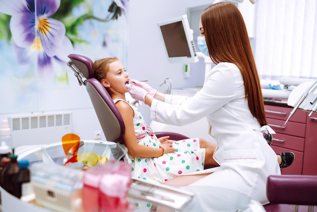 Photo jolie petite fille souriante après avoir fait un examen dans une stomatologie pédiatrique soins des dents de lait