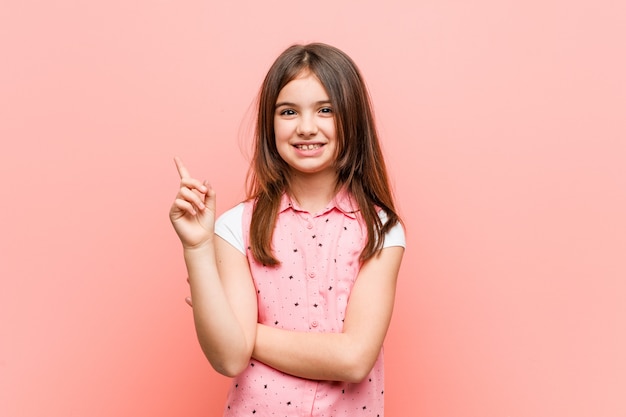 Jolie petite fille souriante pointant gaiement avec l'index.