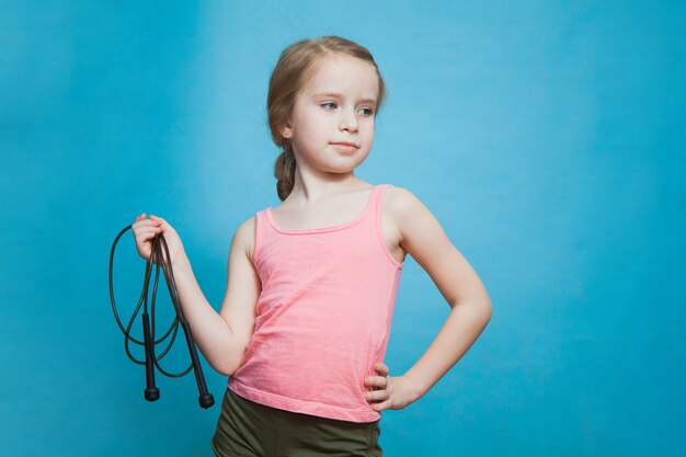 Jolie petite fille sportive avec corde à sauter sur bleu