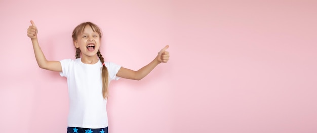 Jolie petite fille en t-shirt blanc souriant sur fond rose