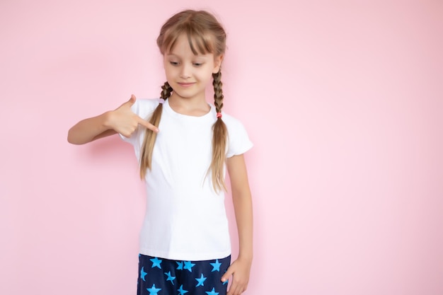 Jolie petite fille en t-shirt blanc souriant sur fond rose