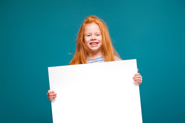 Jolie petite fille en tee-shirt avec de longs cheveux tient du papier propre