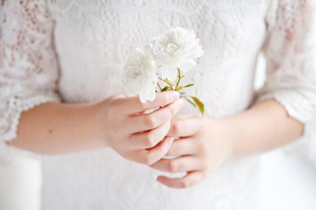 Jolie petite fille tenant une fleur rose. Fleurs en mains féminines se bouchent