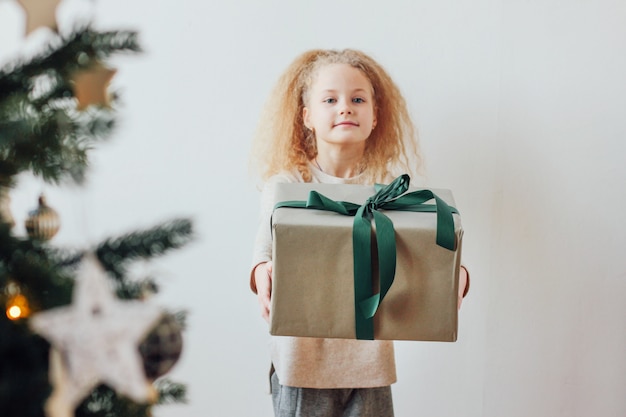 Jolie petite fille tenant une grande boîte-cadeau, le temps de Noël