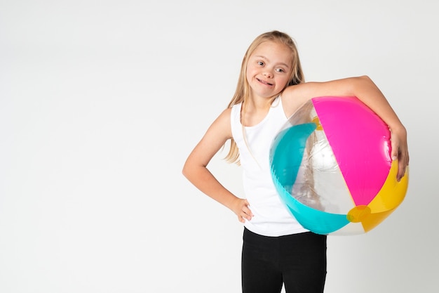 Jolie petite fille trisomique avec un ballon de plage