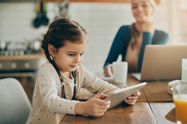 Jolie petite fille utilisant une table numérique tout en se relaxant à la maison