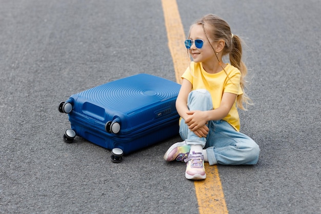 jolie petite fille avec une valise en plein air