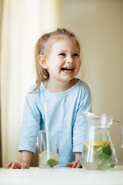 Jolie petite fille avec un verre d'eau dans la cuisine