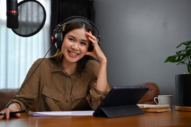 Jolie podcasteuse indépendante asiatique exécutant son émission en ligne dans un home studio