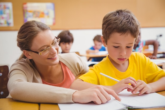 Jolie professeur aidant l&#39;élève en salle de classe