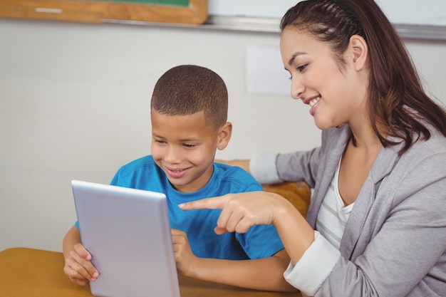 Jolie professeur et élève avec tablette à son bureau