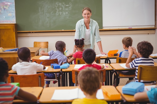 Jolie professeur parlant aux jeunes élèves dans la salle de classe