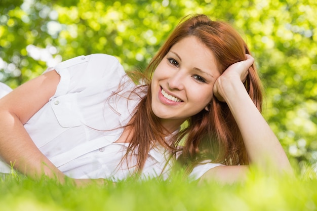 Jolie rousse allongée sur l&#39;herbe, souriant à la caméra