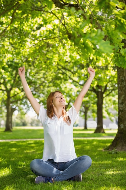 Jolie rousse levant les bras dans le parc