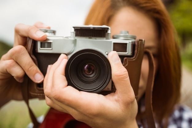 Jolie rousse prenant une photo avec un appareil photo rétro