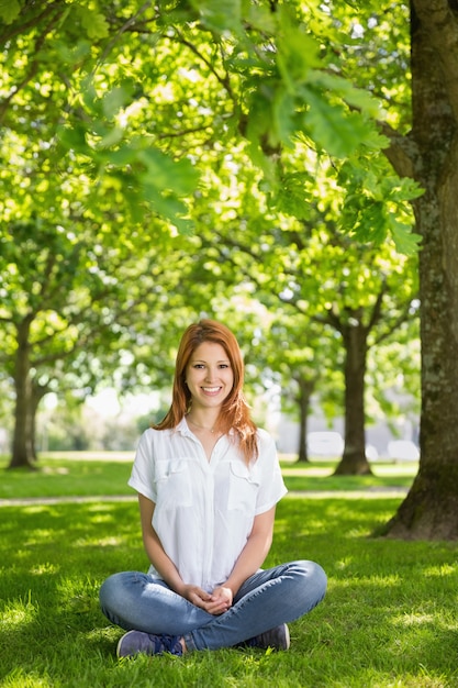 Jolie rousse, souriant à la caméra dans le parc