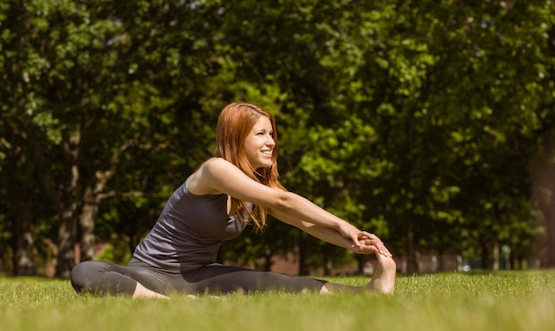 Jolie rousse souriante qui s&#39;étend dans le parc