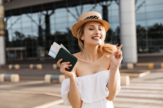 Une jolie touriste blonde détient un passeport et croise les doigts