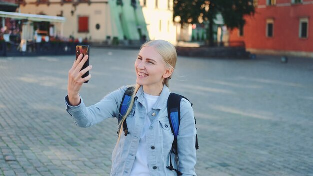 Jolie touriste faisant appel vidéo sur smartphone depuis le lieu de sa visite