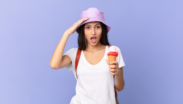 Jolie touriste hispanique à l'air heureux étonné et surpris et tenant une glace