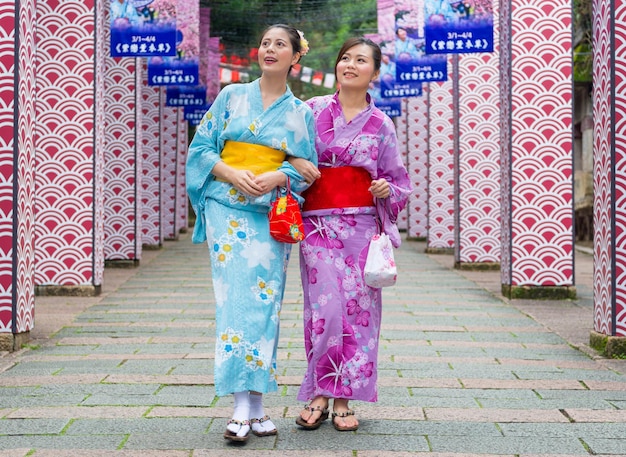 de jolies copines heureuses portant des vêtements traditionnels habillent un kimono rejoignant ensemble la célébration du festival japonais et marchant sur le sentier de l'histoire en regardant la culture japonaise pendant les vacances d'été.