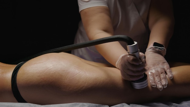 Jolies fesses et jambes femme recevant un massage anticellulite anti-âge levage sous vide rf dans un salon de spa bien-être soins de la peau du corps traitement de beauté procédure de rajeunissement fond noir foncé