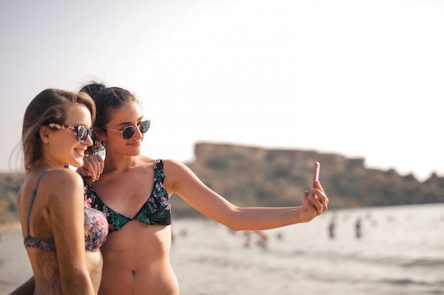 Jolies filles prenant un selfie sur la plage