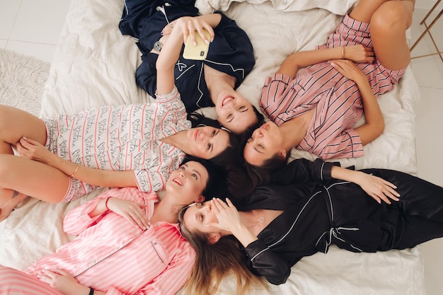 Jolies filles en pyjama prenant selfie sur le lit