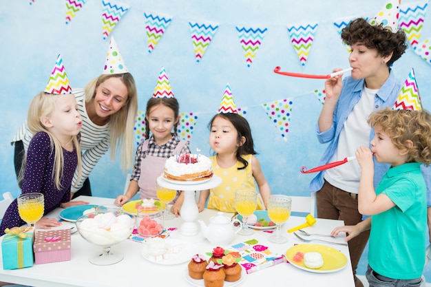 Jolies filles soufflant des bougies sur le gâteau