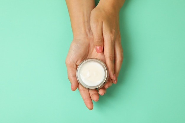 Photo jolies mains féminines tiennent le pot de crème cosmétique isolé