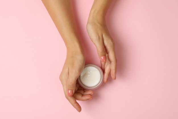 Jolies mains féminines tiennent le pot de crème cosmétique