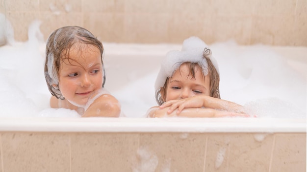Jolies soeurs filles dans le bain avec de la mousse de savon