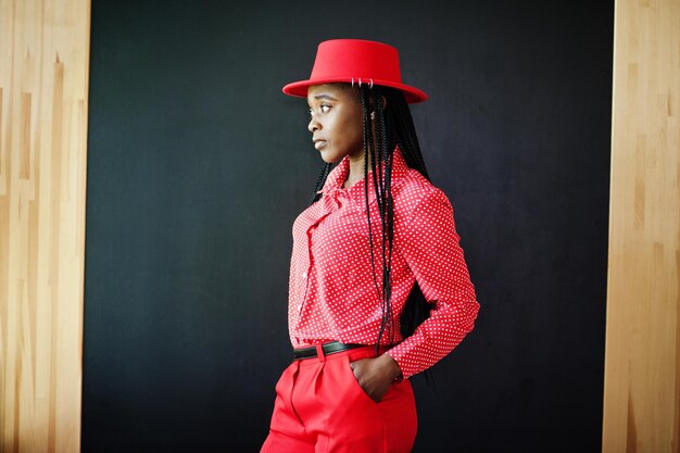 Photo jolies tresses affaires femme afro-américaine brillante personne autoritaire amicale porter bureau chemise rouge chapeau et pantalon