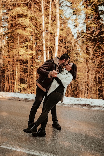 Jolis partenaires de vie de couple attrayants dans des journées d'hiver douillettes dansant et s'embrassant sur fond d'autoroute enneigée Mise au point sélective