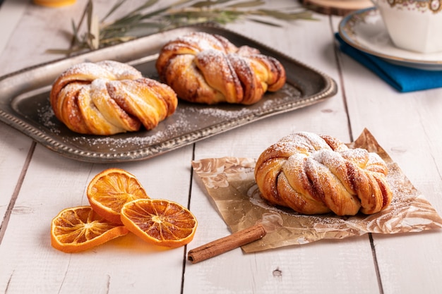 De jolis petits pains noués à la cannelle sur une table en bois blanc