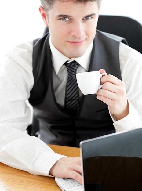 Jolly jeune homme d&#39;affaires en regardant la caméra tenant un café