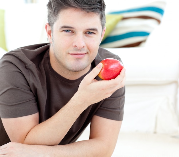 Jolly man tenant une pomme rouge allongé sur le sol