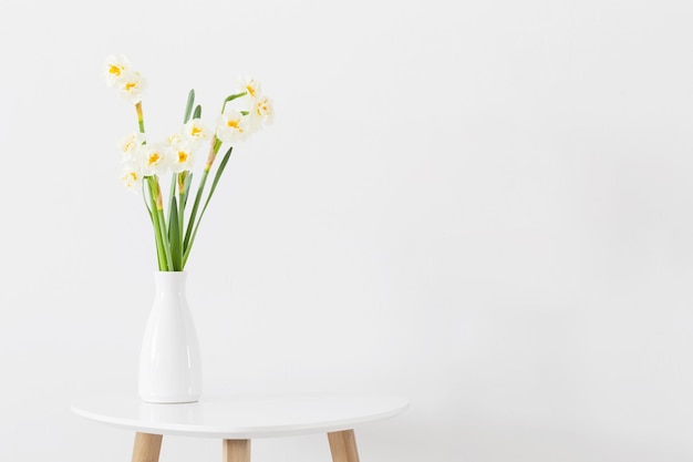 Jonquilles dans un vase blanc sur fond blanc