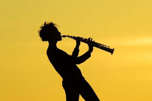 Jouant du saxophone silhouette sur fond jaune