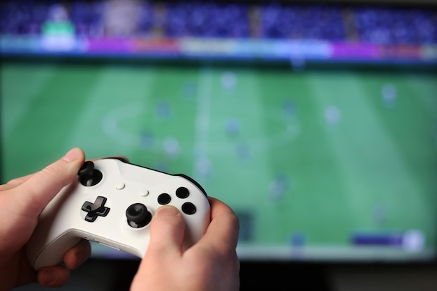 Joue au football à la télé, tenant une manette blanche