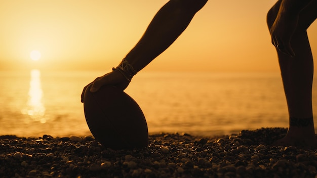 Jouer au football sur la plage au coucher du soleil