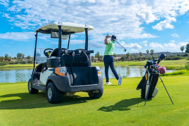 Jouer au golf professionnel sur un terrain de golf en frappant la balle près d'un buggy de lac