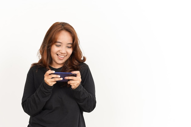 Jouer au jeu mobile sur smartphone de la belle femme asiatique portant une chemise noire isolée sur blanc