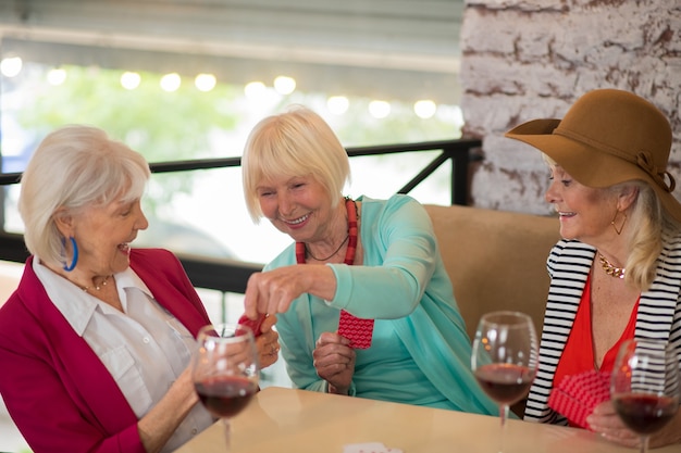 Jouer aux cartes. Belles femmes gaies senior jouant aux cartes et semblant appréciées