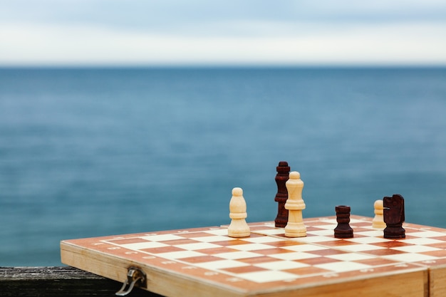 Jouer aux échecs sur une planche sur la plage. Échiquier sur mer par une journée ensoleillée. Vacances sur la côte.