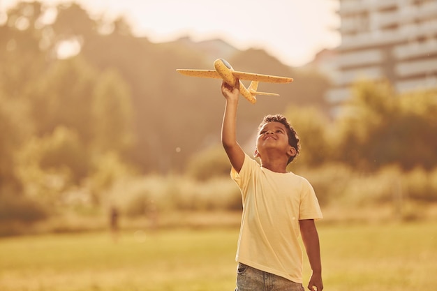 Jouer avec l'avion Un enfant afro-américain s'amuse sur le terrain pendant la journée d'été