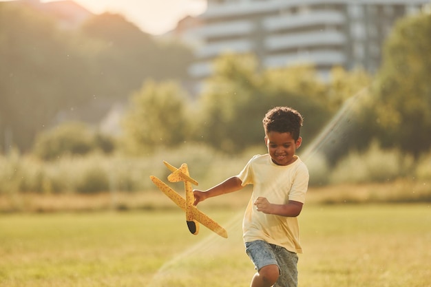 Jouer avec l'avion Un enfant afro-américain s'amuse sur le terrain pendant la journée d'été