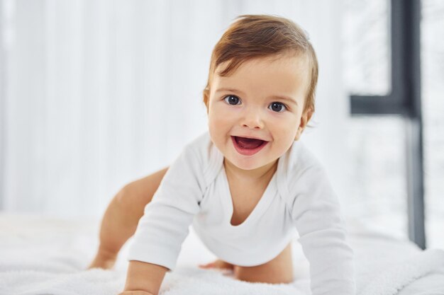 Jouer sur le lit Joli petit bébé est à l'intérieur dans la chambre domestique