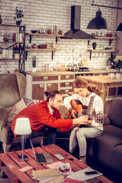 Jouer la mélodie. Frère et sœur regardant une vidéo sur un ordinateur portable et jouant la mélodie à la guitare