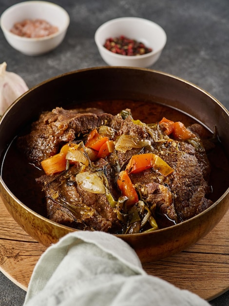 Joues de boeuf braisées allemandes traditionnelles dans une sauce au vin rouge brun avec des herbes comme gros plan dans une poêle